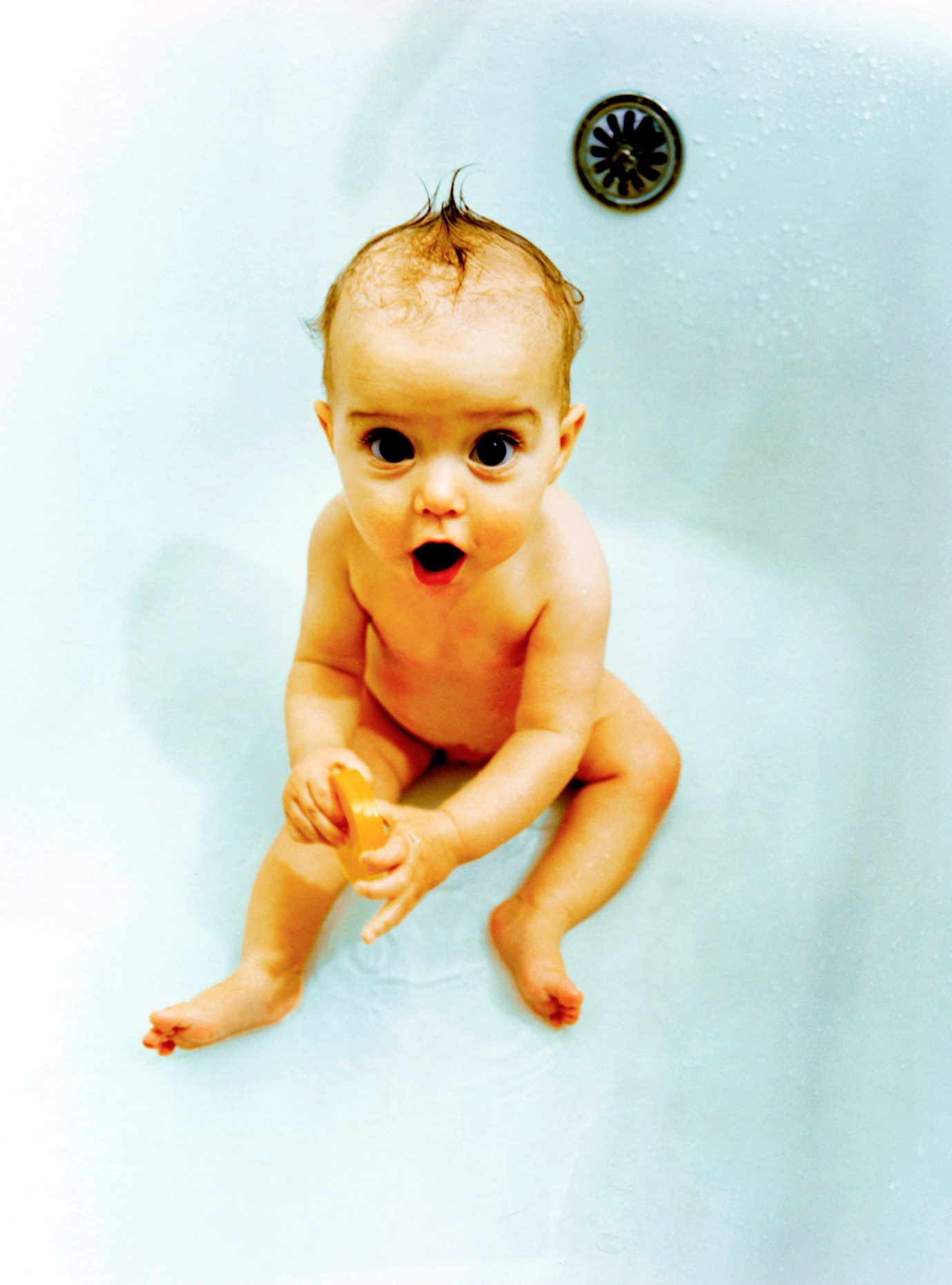 Baby girl (6-12 months old) plays in bathtub.