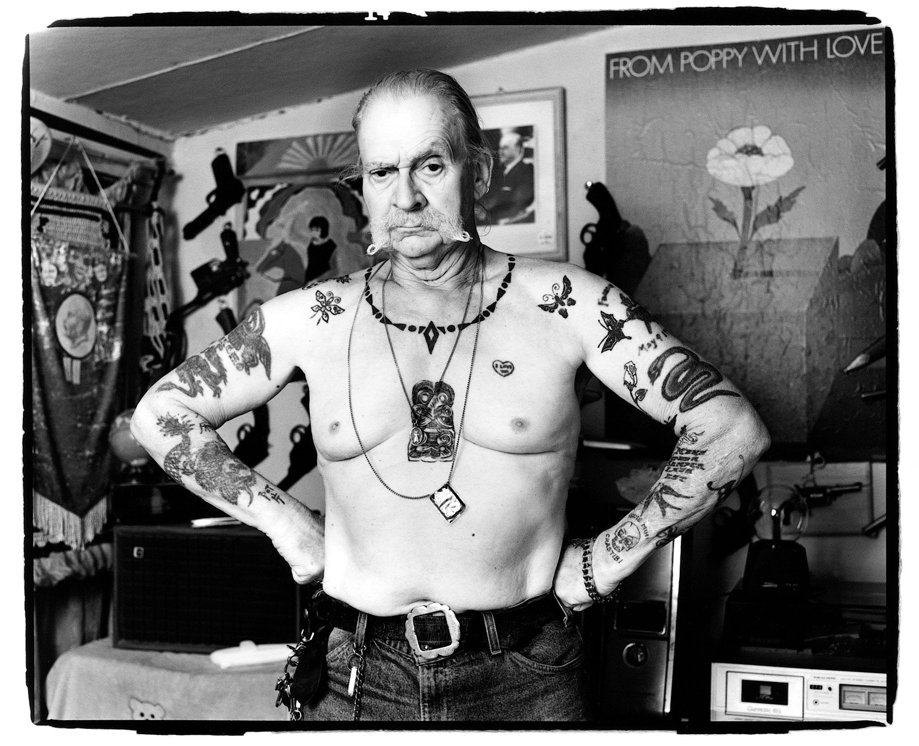 Frank Hillary stands shirtless showing off his tattoos in front of his gun collection in Tucson, AZ.