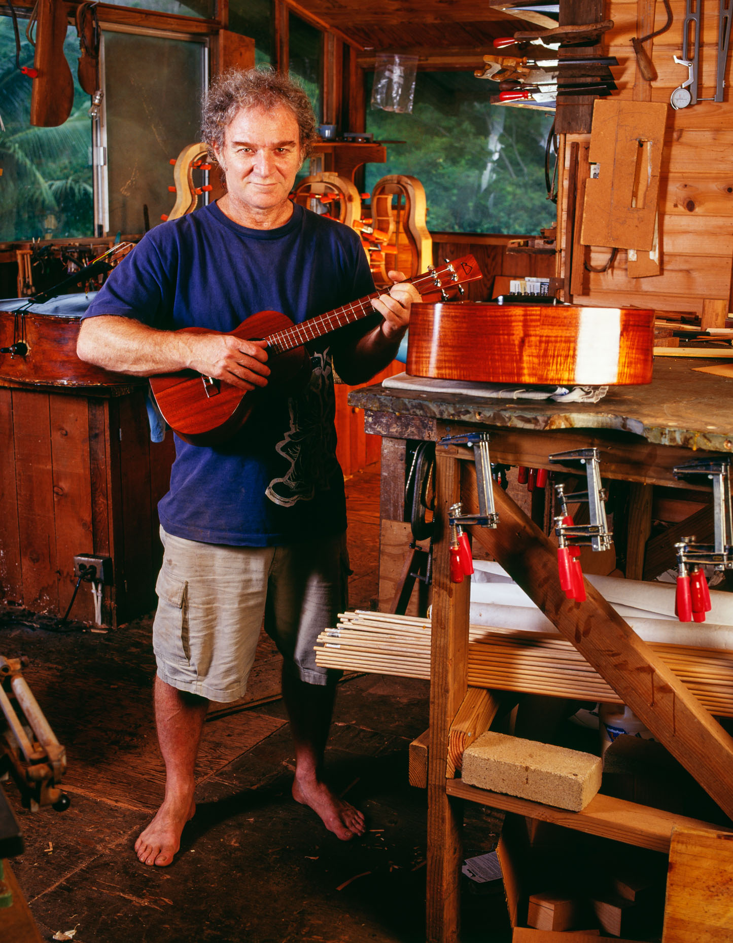 Luthier (Mature man) playing ukelele in his workshop, portrait